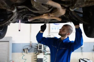 Mechanic inspecting a car's exhaust system underneath the vehicle