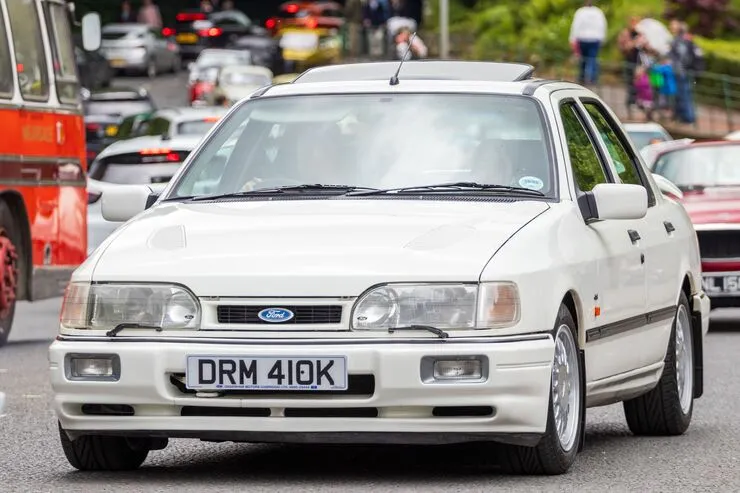 White Ford Sierra RS Cosworth driving along a street in Morpeth, England.