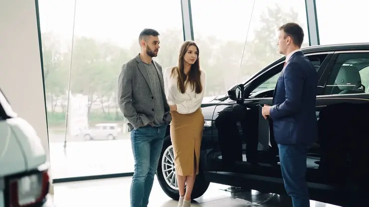 Couple discussing a car purchase with a salesperson in a dealership