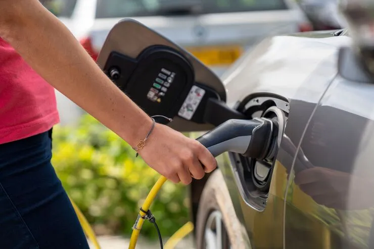 Driver plugging an electric car into a public charging point in England