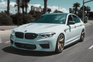 White BMW car driving on the road with the windows down, black out windows, clear blue skies