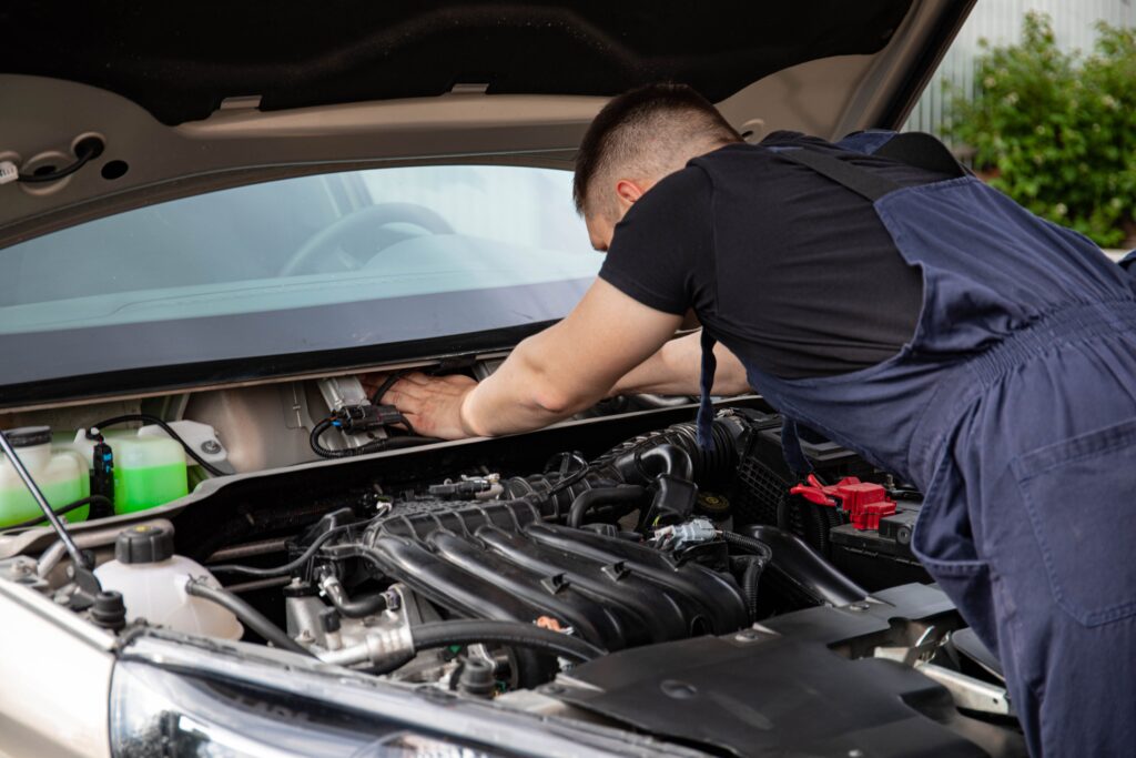 Mechanic inspecting a car engine as part of a vehicle maintenance check