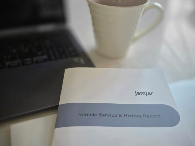 jamjar car service history book beside a laptop and coffee cup