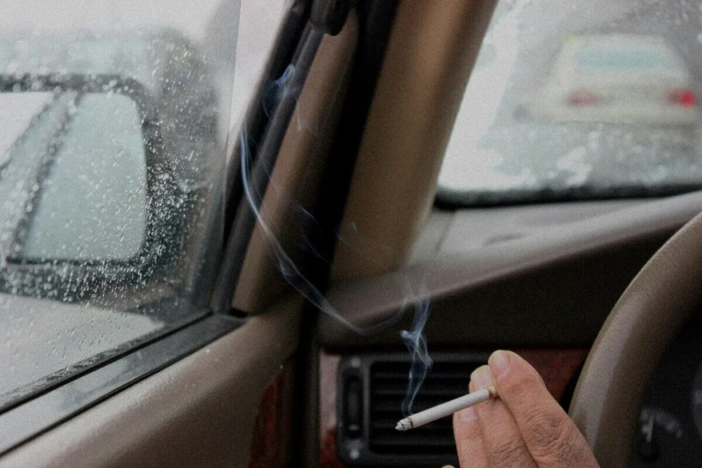 Cigarette beside an ashtray inside an older car